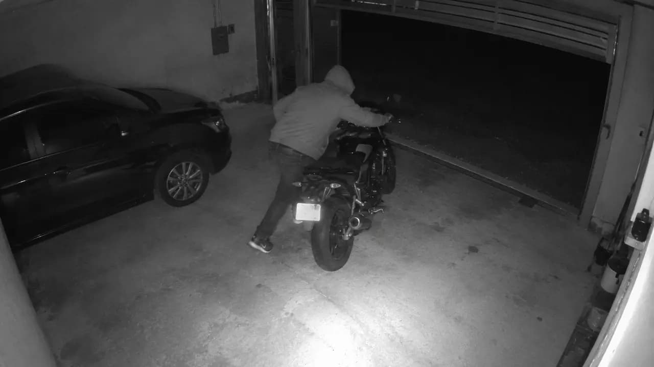 Câmera 3: pessoa encapuzada furtando uma moto na garagem